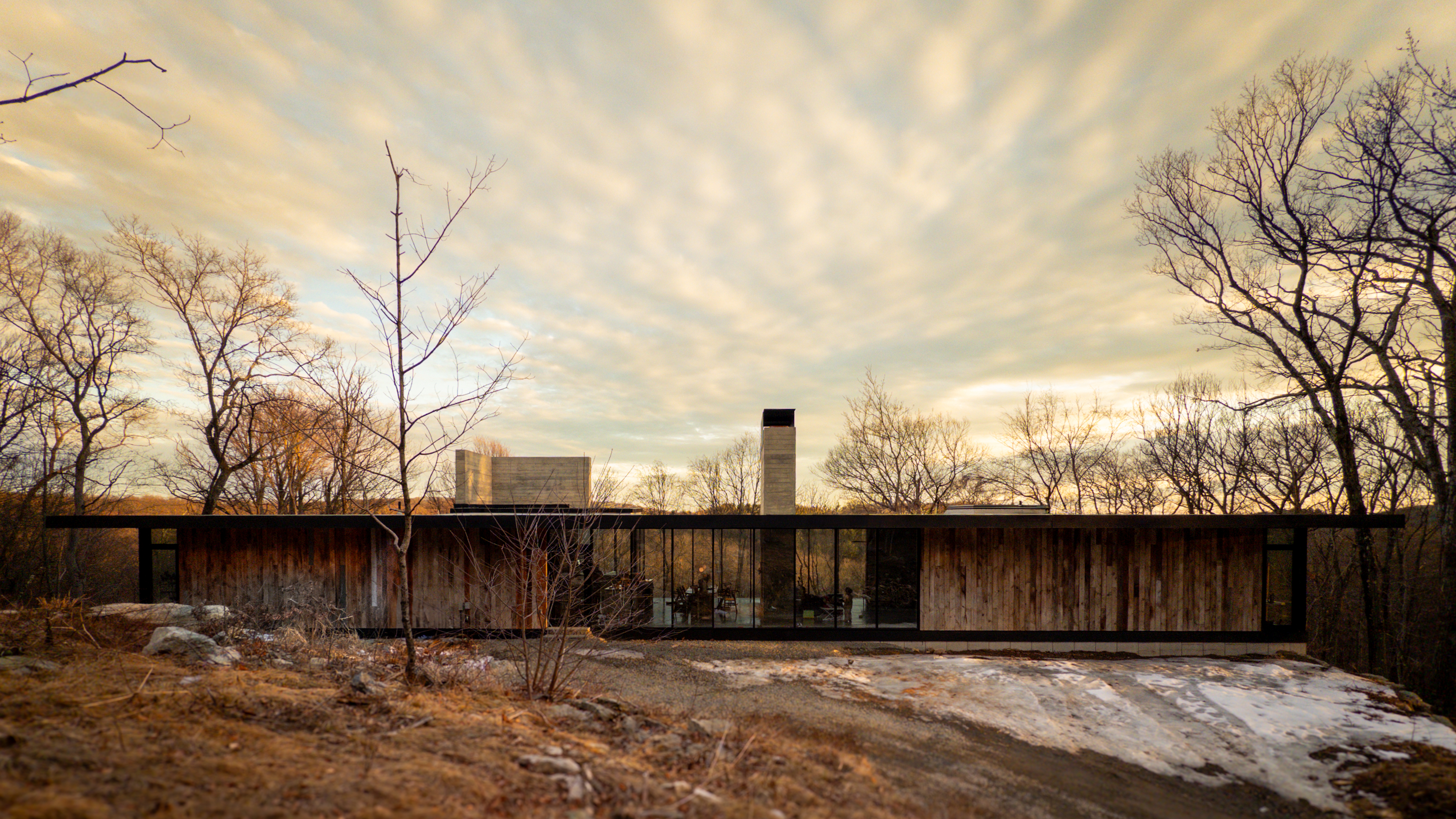 North elevation at dusk, cantilever and chimney over cleared ridge